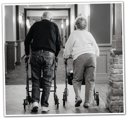 Two residents walking down a corridor with walkers
