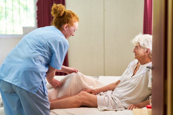 Caregiver assisting a resident in a cozy bedroom