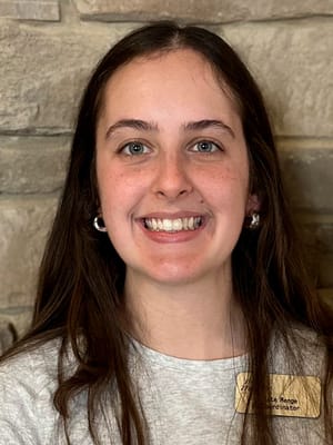 Staff member smiling in front of a stone wall