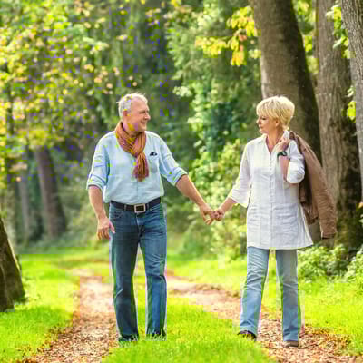 Couple walking hand in hand along a tree-lined path