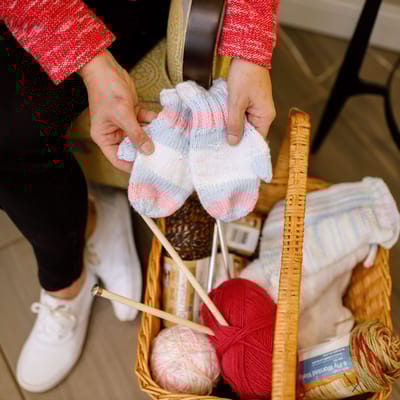 A resident crafting colorful mittens with yarn