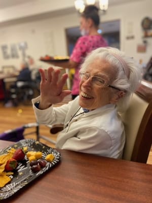 A smiling resident waving while enjoying snacks
