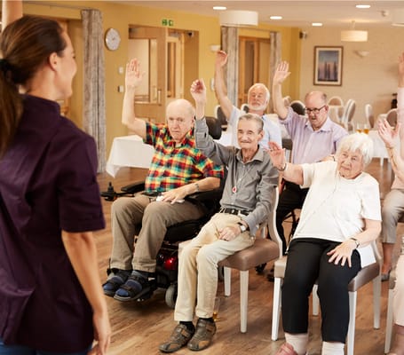 Residents engaged in an activity session with raised hands