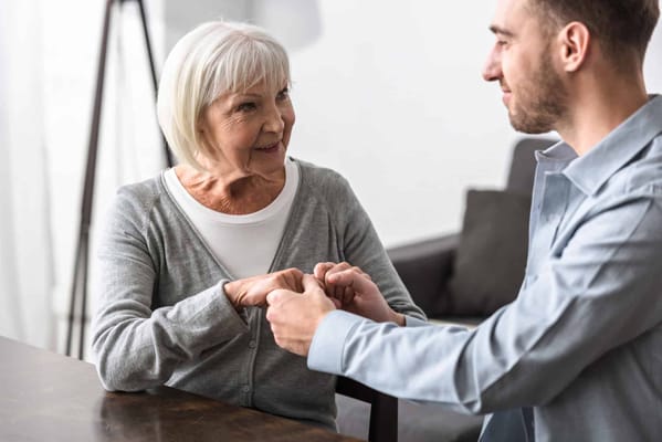 A caregiver holding hands with a smiling senior resident