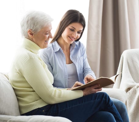 Two women engaging in a reading activity indoors