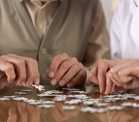 Residents and staff working on a puzzle together