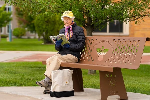 Resident reading on a bench in a garden