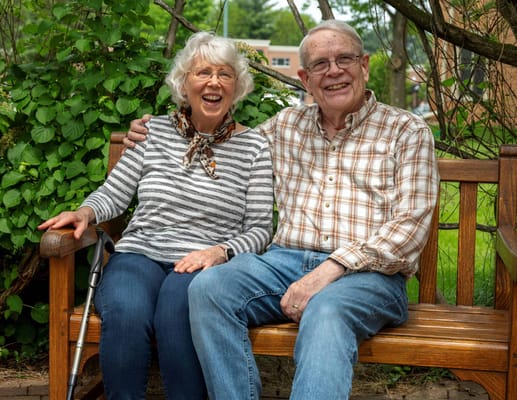 Two smiling residents sitting together on a bench outdoors