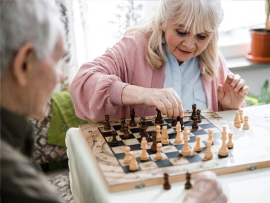 Two residents engaging in a game of chess indoors
