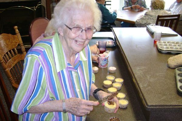Senior resident decorating cupcakes in a common area