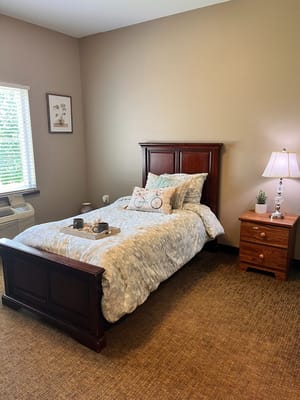 A cozy private resident room with a bed and bedside table