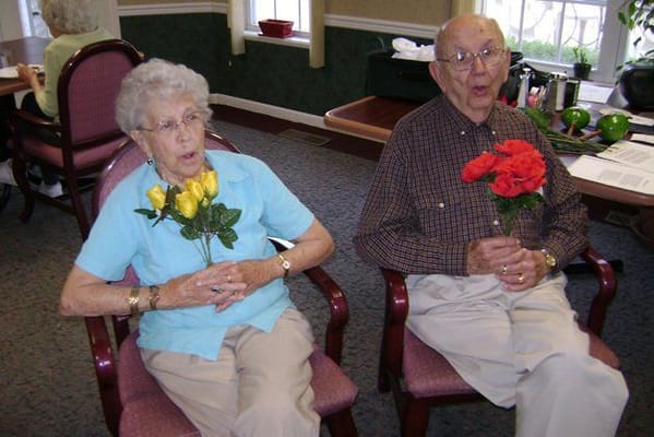 Two residents holding flowers in an activity room