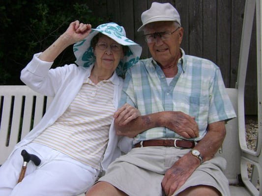 Elderly couple sitting together outdoors, smiling