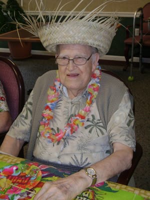 Senior resident enjoying a festive activity with a hat and lei