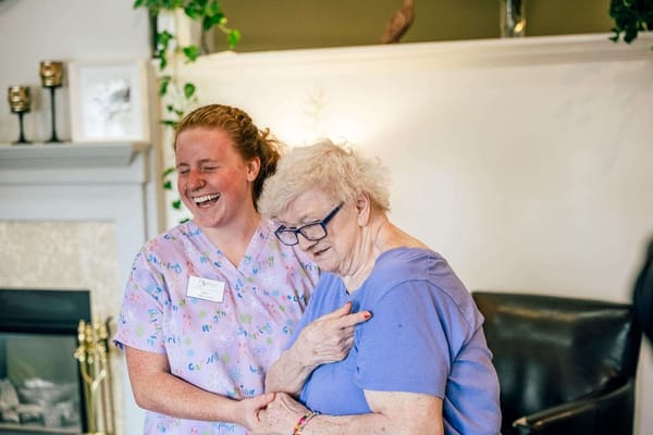 A caregiver and a resident sharing a joyful moment indoors