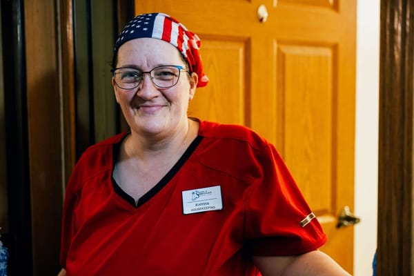 Staff member smiling in a red uniform