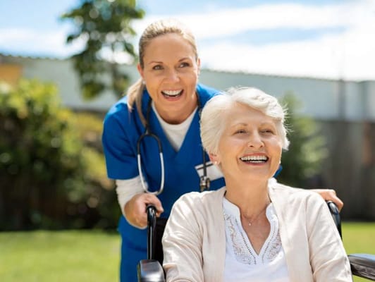 Healthcare worker assisting a smiling resident outdoors