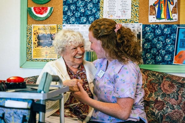A staff member and resident smiling together in a social space