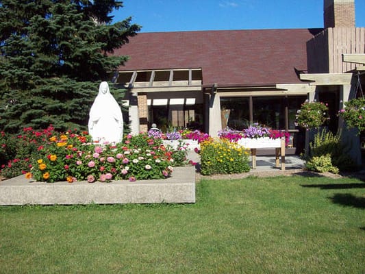 Exterior view of St Monicas Senior Living with flower beds