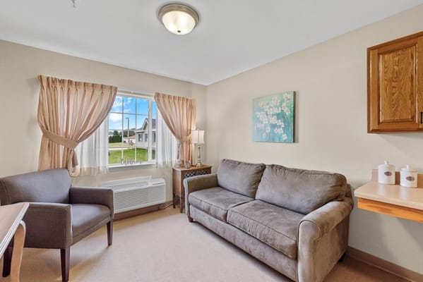 A cozy resident room with a couch and a window view