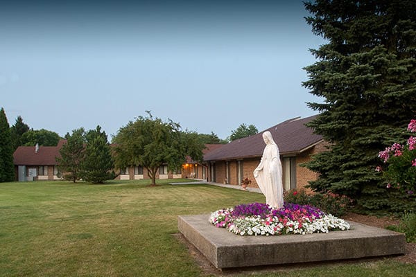 Outdoor view of a senior living facility with a statue and flowers