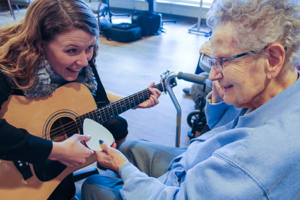 A staff member playing guitar with a resident