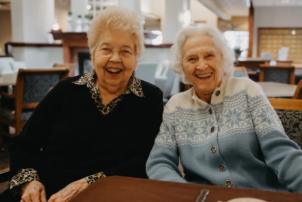 Two women smiling together in a dining area
