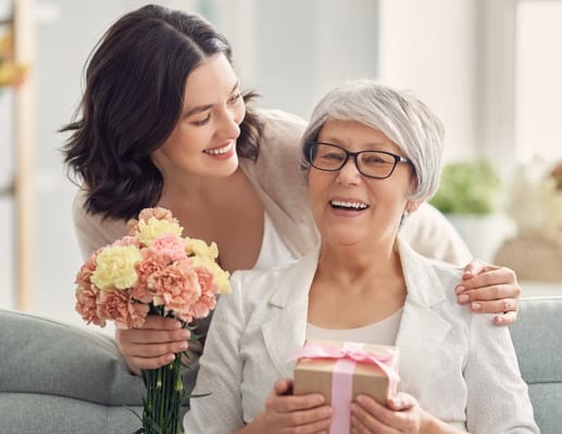 Smiling residents celebrating with flowers and a gift