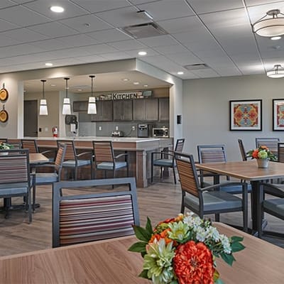 Bright dining area with tables and kitchen in the background