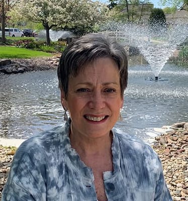 Woman smiling by a pond with a fountain