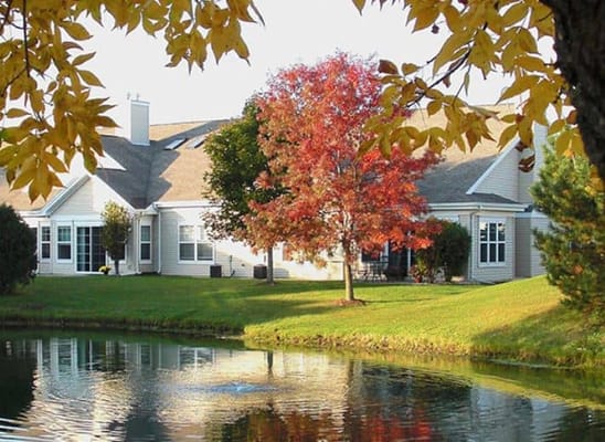 Exterior view of assisted living facility with a pond and trees
