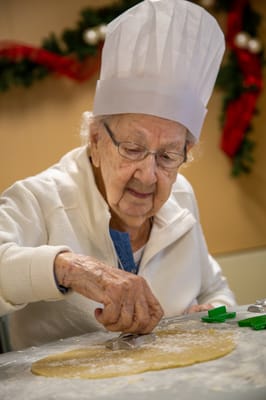 An elderly woman baking cookies in a cozy kitchen