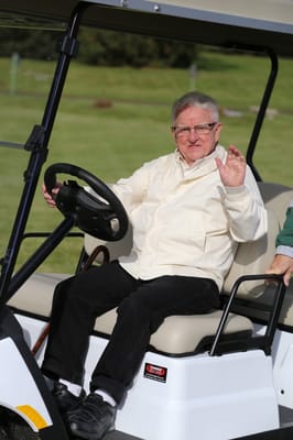 Resident driving a golf cart in a sunny outdoor area