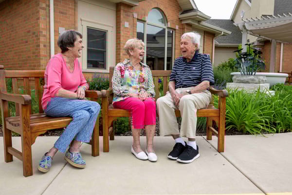 Three residents enjoying time together on a bench outside