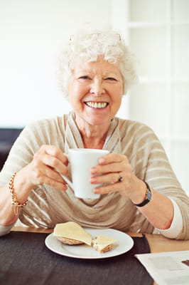 Senior woman enjoying a snack and a drink