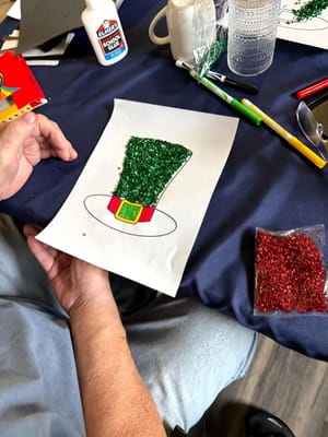 A resident creating a holiday craft with glitter