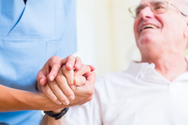 A caregiver holding hands with a smiling resident