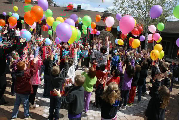 Children and residents celebrating with balloons in a courtyard