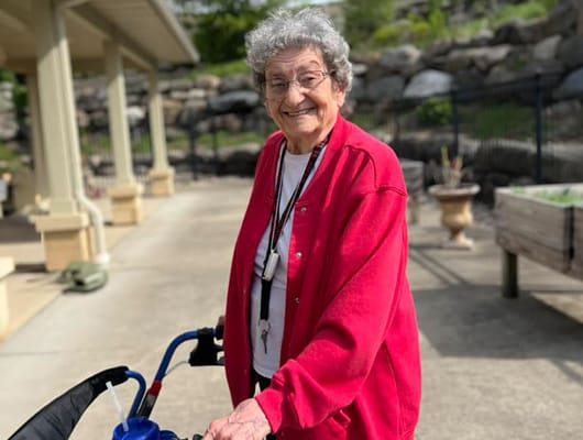 Resident smiling outdoors with a walker