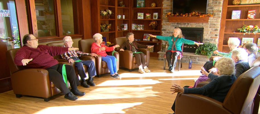 Residents participating in a seated exercise class in a common area