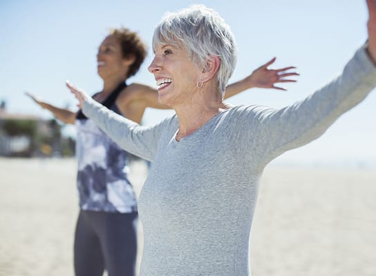 Residents participating in an outdoor exercise class by the beach.