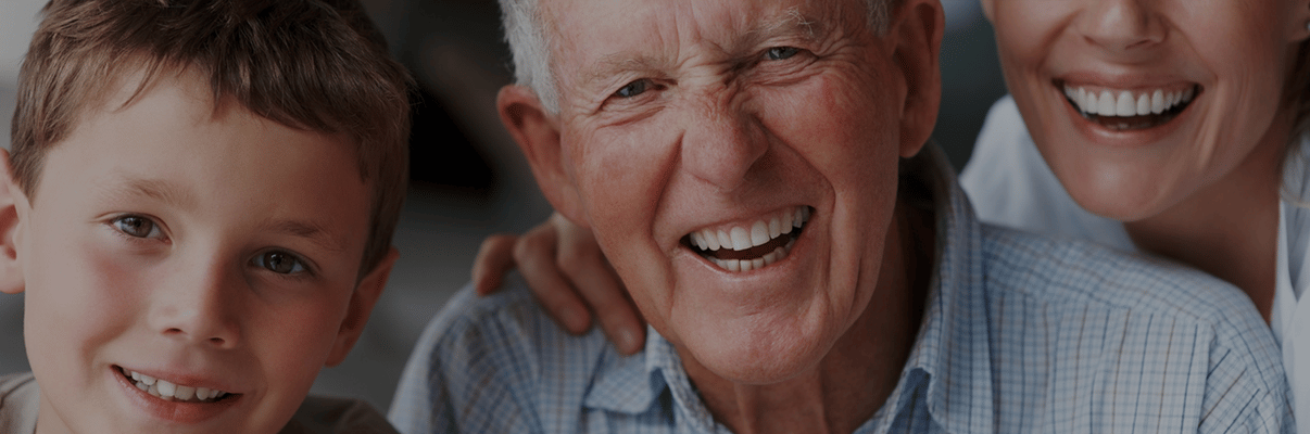 A smiling elderly man with a child and a caregiver
