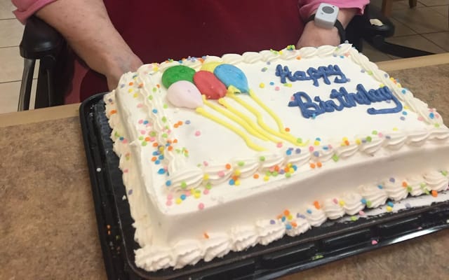 A birthday cake decorated with balloons and colorful sprinkles