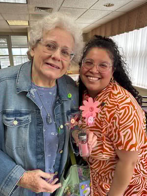 Residents and staff smiling with a floral craft project
