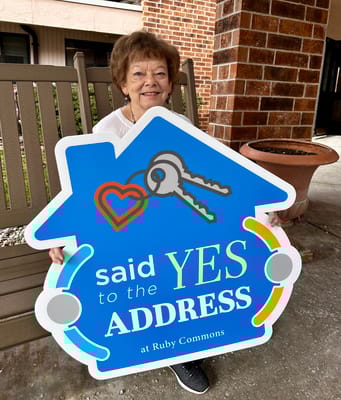 Resident holding a painted sign outside Ruby Commons