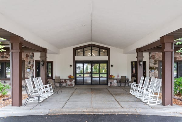Covered entrance with rocking chairs and landscaped area
