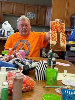 Resident showcasing artwork in an activity room