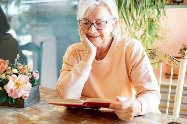 A senior woman enjoying a book at a table