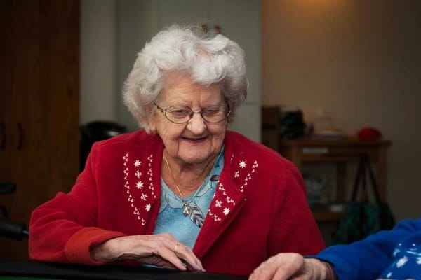 Elderly woman smiling while seated at a table