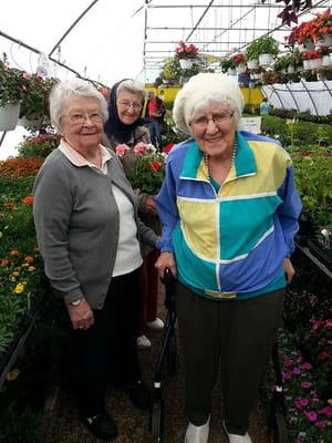 Three residents enjoying flowers in a greenhouse setting